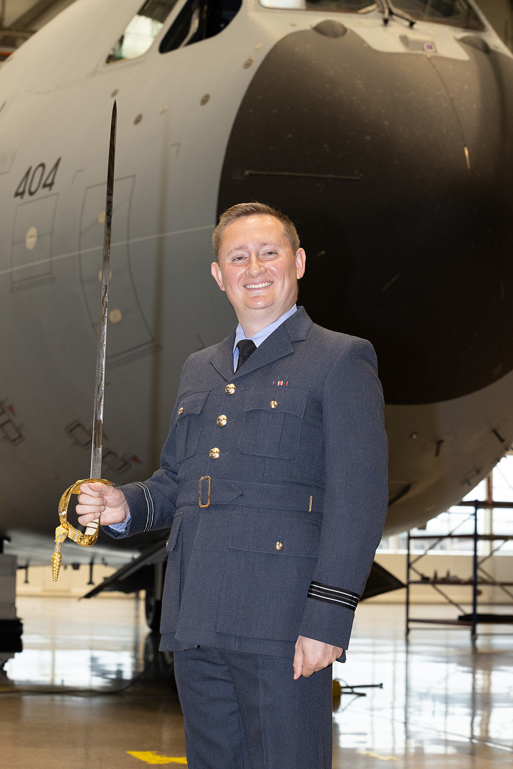 Flight Lieutenant Ewers stands at attention, while proudly holding the Logistics Profession’s Gill Sword upright.